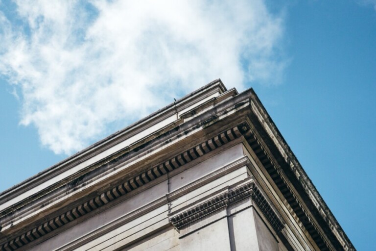 Low angle shot of an architectural building under a clear blue sky with white clouds