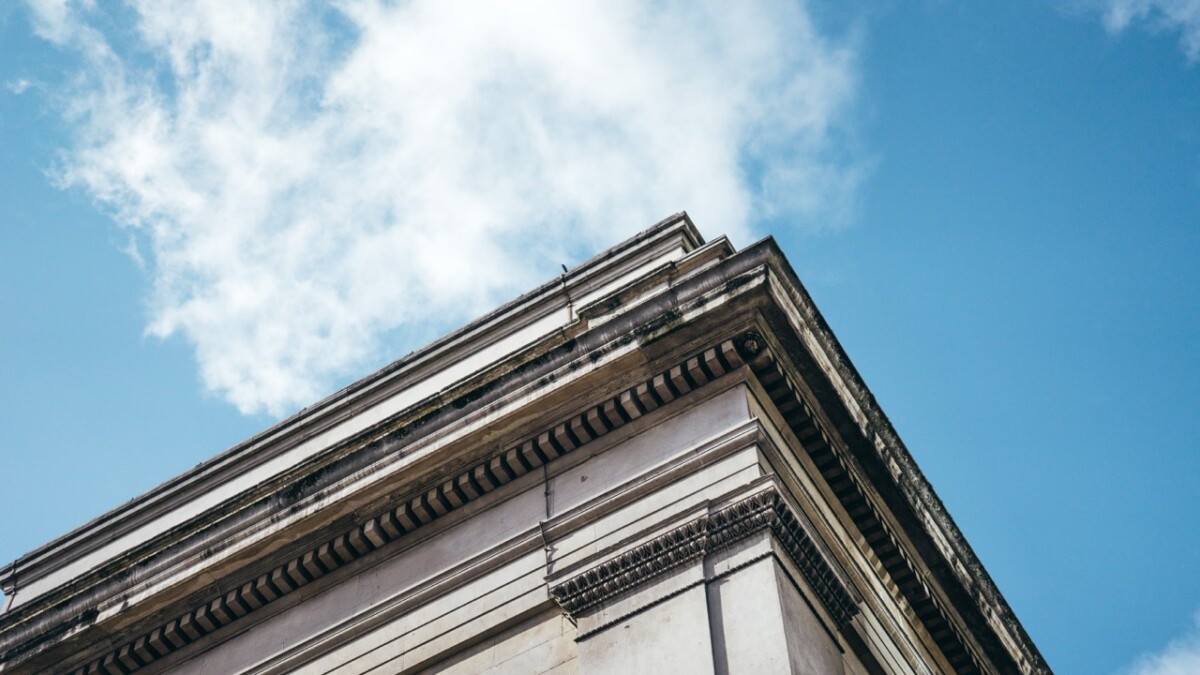 Low angle shot of an architectural building under a clear blue sky with white clouds